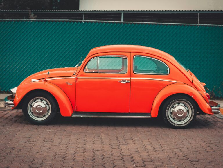 Side view of a classic orange Volkswagen Beetle parked in an urban area in Puebla, Mexico.
